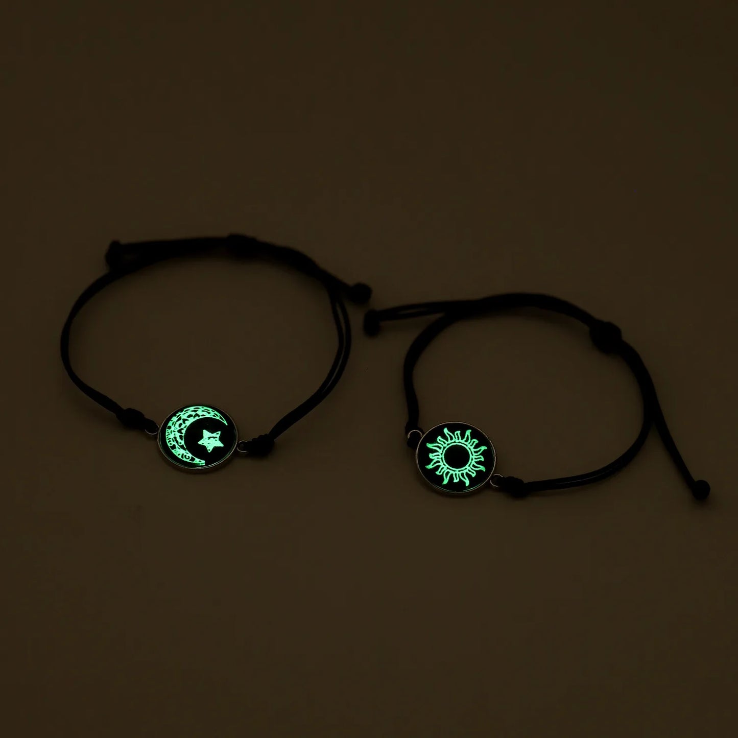 Two black bracelets with glowing green symbols on a dark background