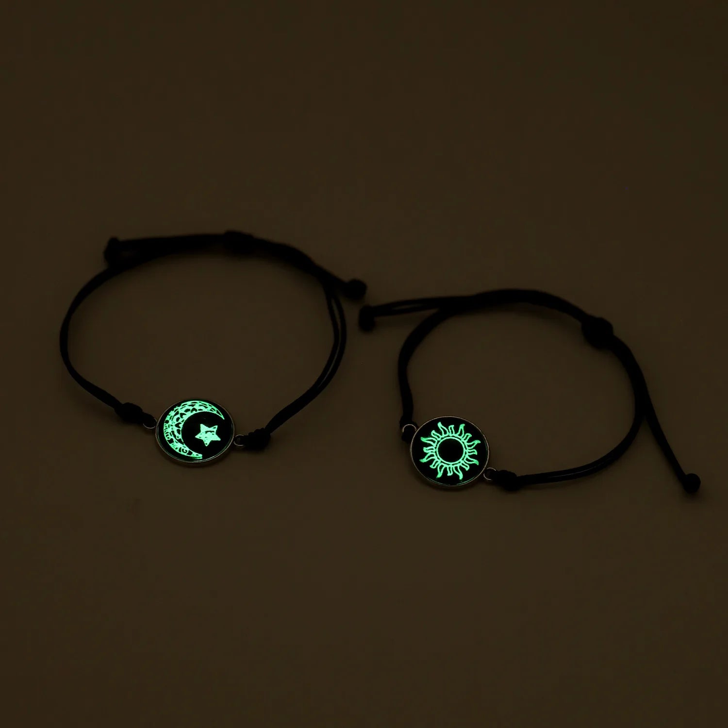 Two black bracelets with glowing green symbols on a dark background