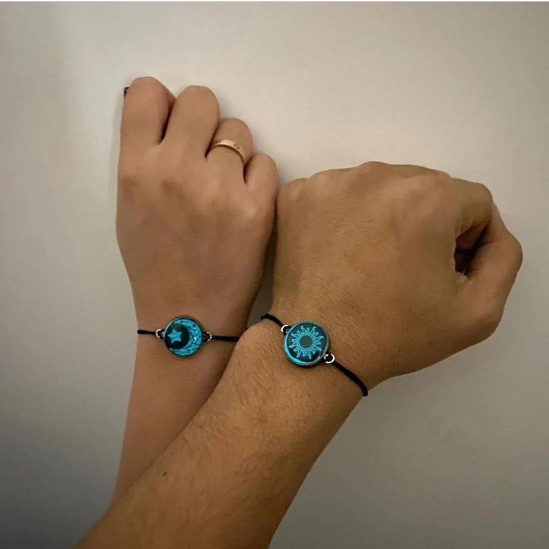 Two wrists wearing blue circular bracelets on a plain background